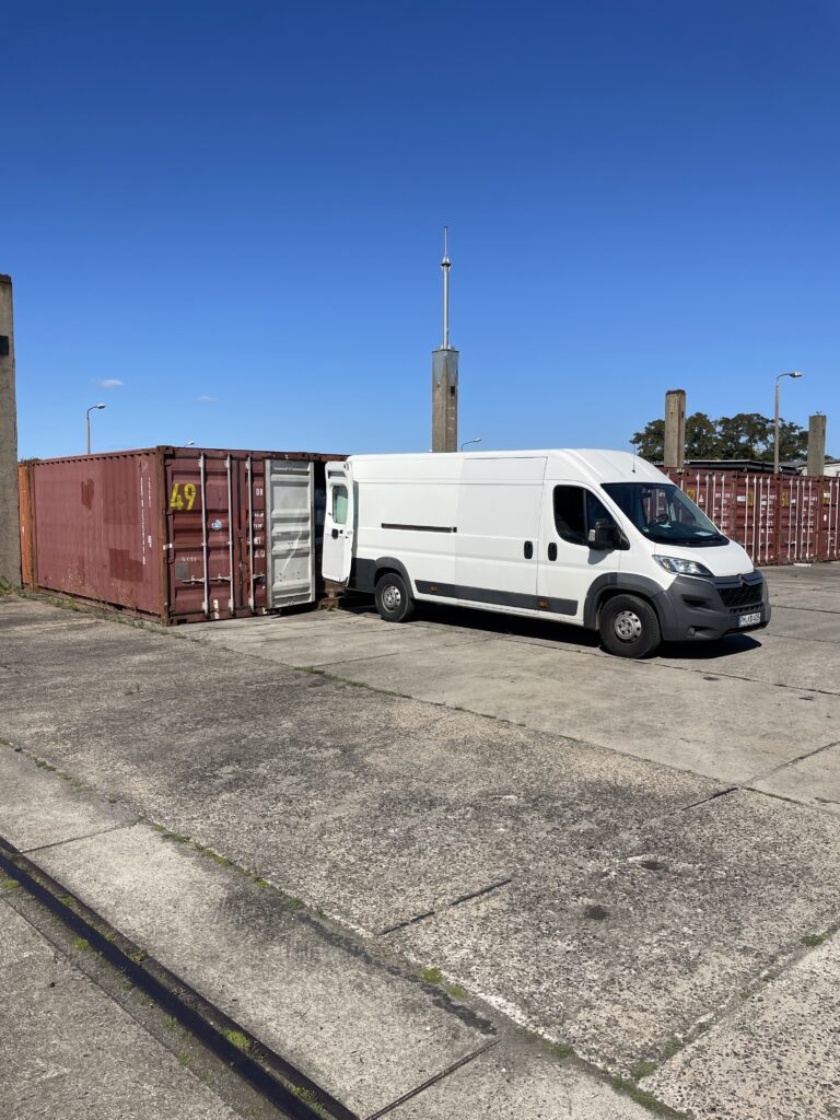 Transporter steht direkt an einem Lagercontainer